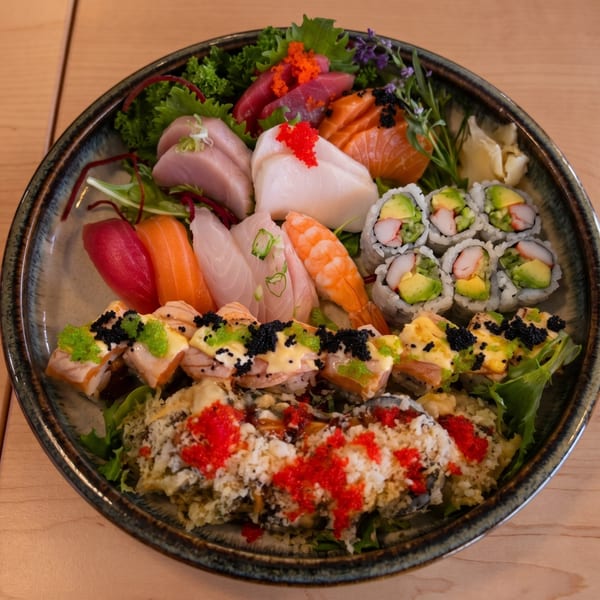 A large platter of assorted sushi, sashimi, and rolls, garnished with roe and greens.